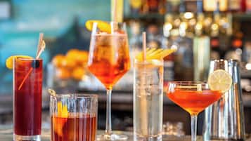 A bar with various drinks, including cocktails and a non-alcoholic option, with a blurred background suggesting a busy environment.