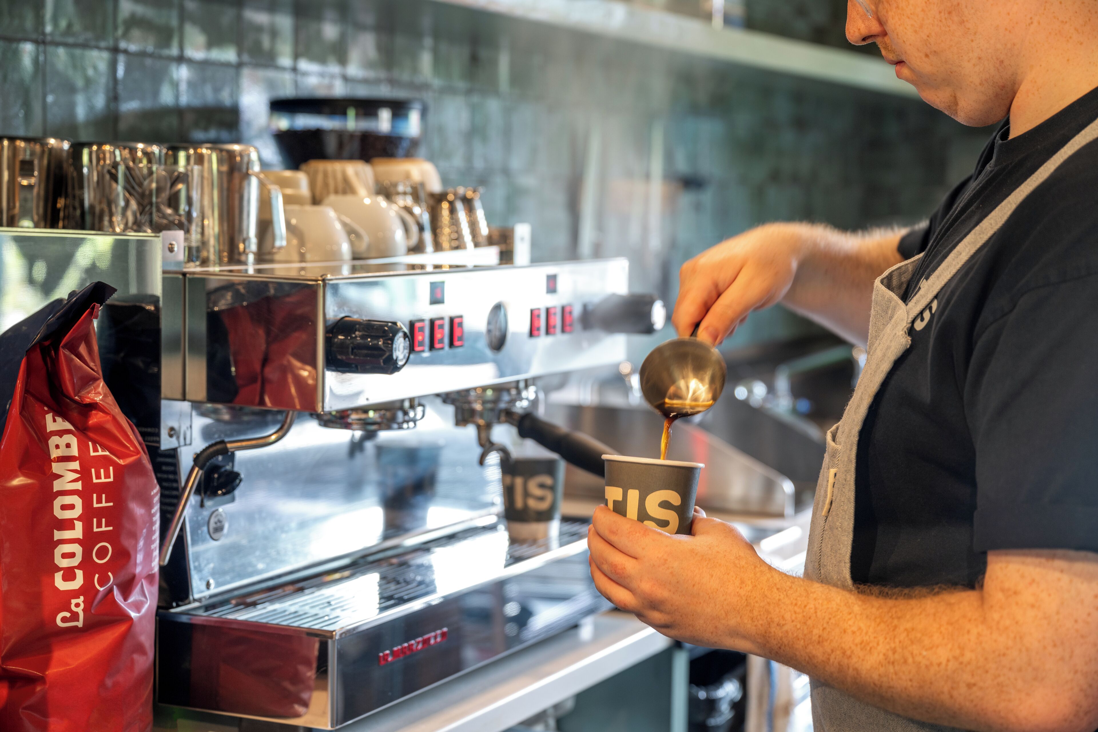 A barista preparing a drink at a coffee machine.
