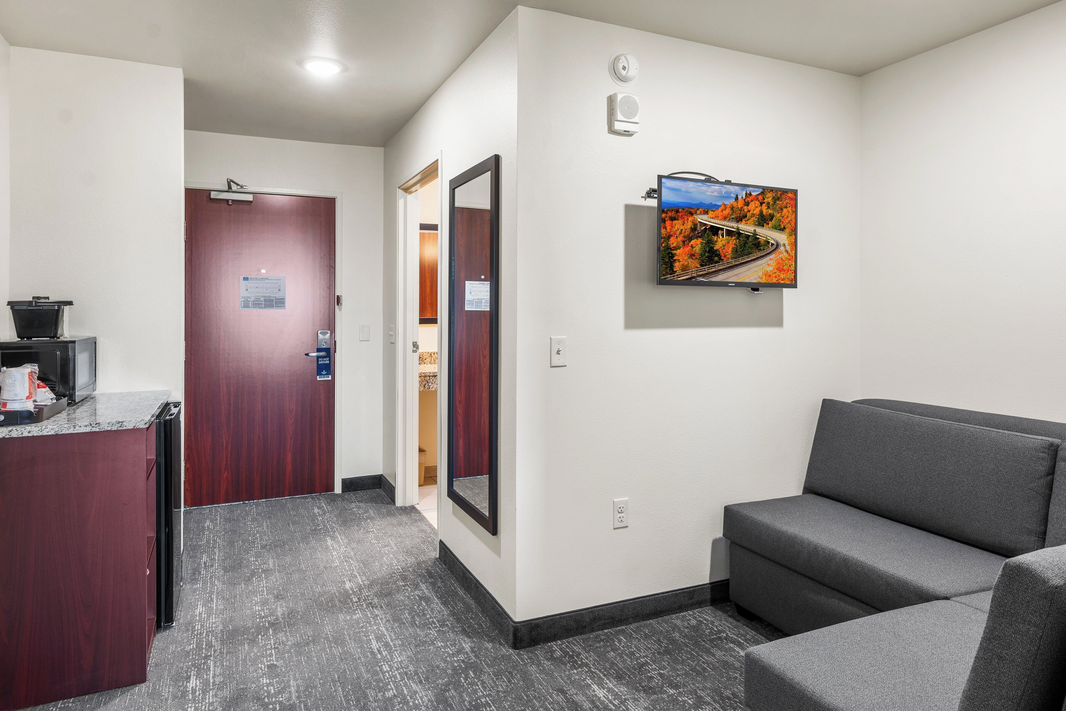 A reception area with a desk, a couch, a TV mounted on the wall, and a door leading to another room.