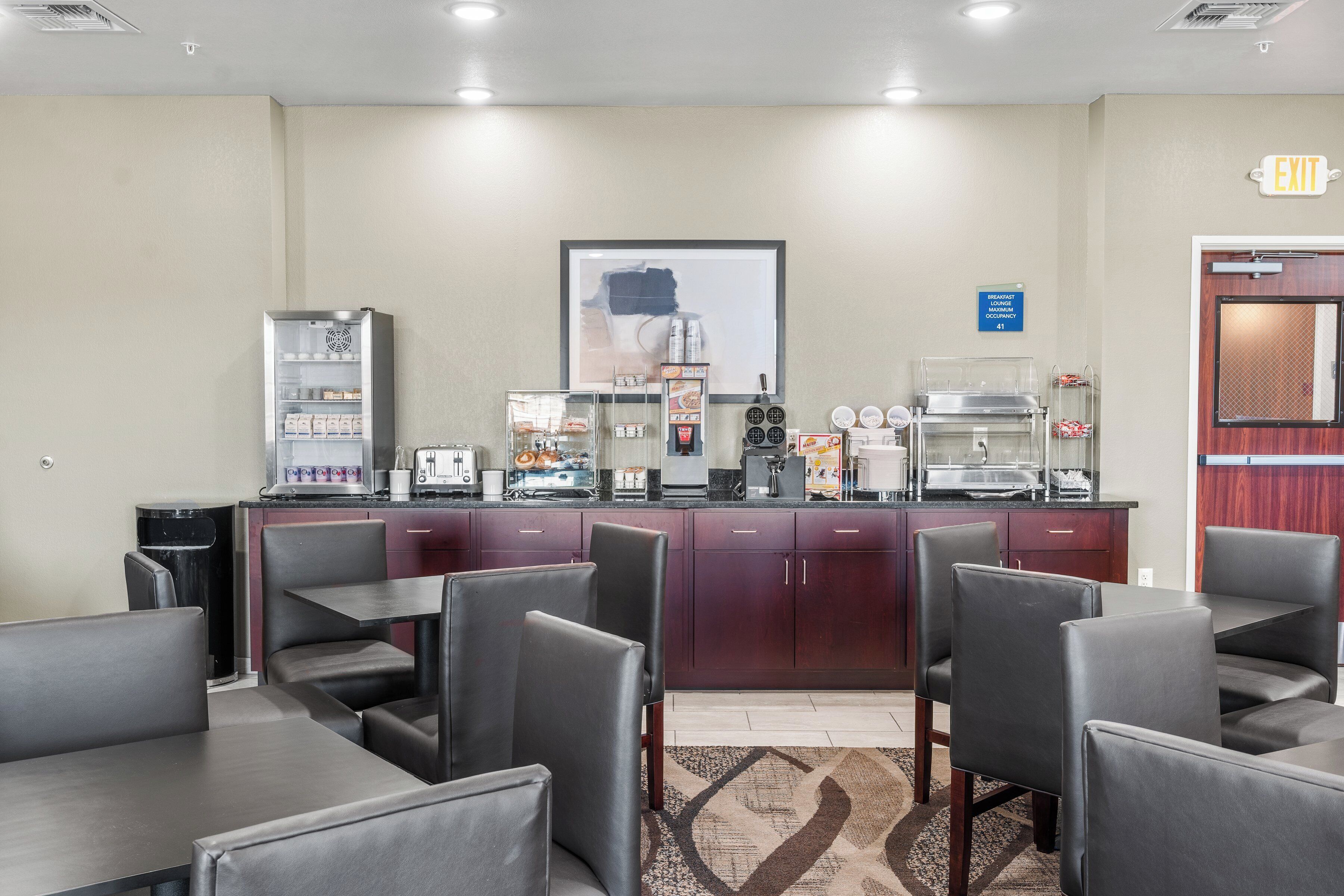 A hotel lobby with a reception desk, seating area, and a refrigerator stocked with beverages.