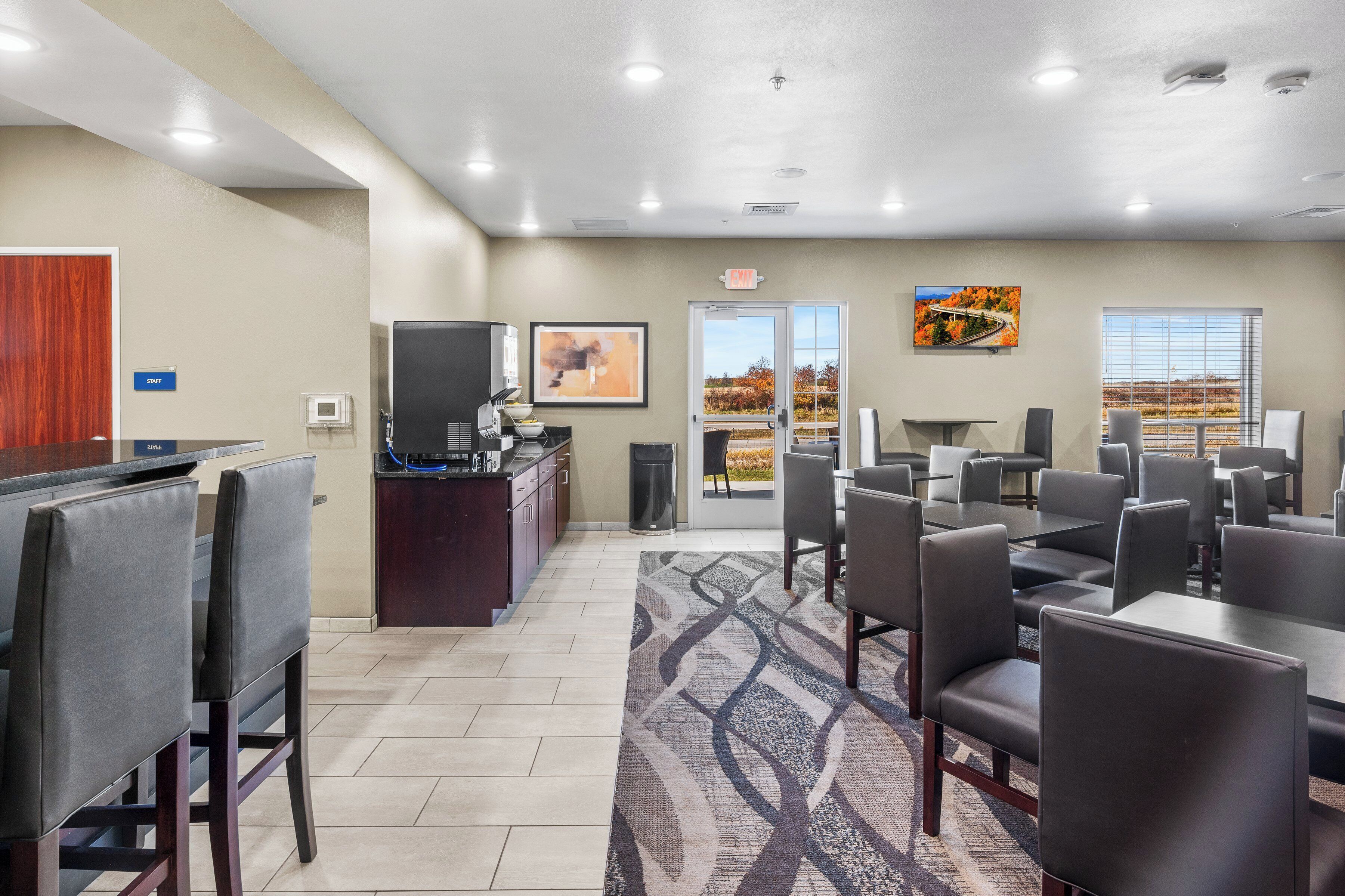 A hotel conference room with a reception desk, seating area, and large windows offering a view of the outdoors.