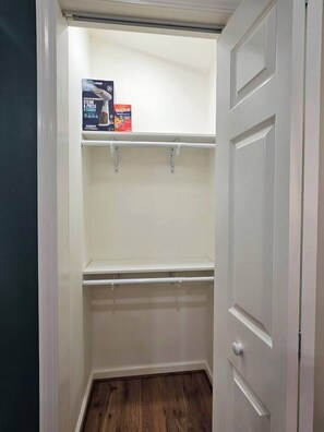 A closet with two shelves, a door, and a wooden floor. - Cozy 1-bdrm/1 bath, desk, grill, deck, laundry (Phenix City)