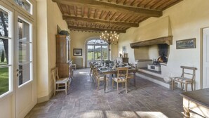 Un espace repas doté d’un plafond en bois, d’une cheminée et offrant une vue sur l’extérieur.