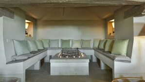Ein gemütlicher Sitzbereich mit Kamin aus Stein, gepolsterten Bänken und einem Steintisch.