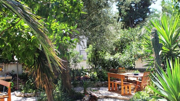 Eine Gartenpatio mit Steinböden, Holzmöbeln und verschiedenen Pflanzen.