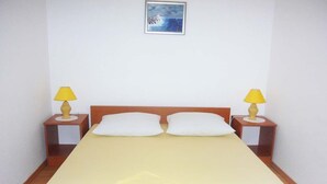 Un letto rifatto con cura, una testiera in legno, due lampade ai comodini e un quadro appeso alla parete.