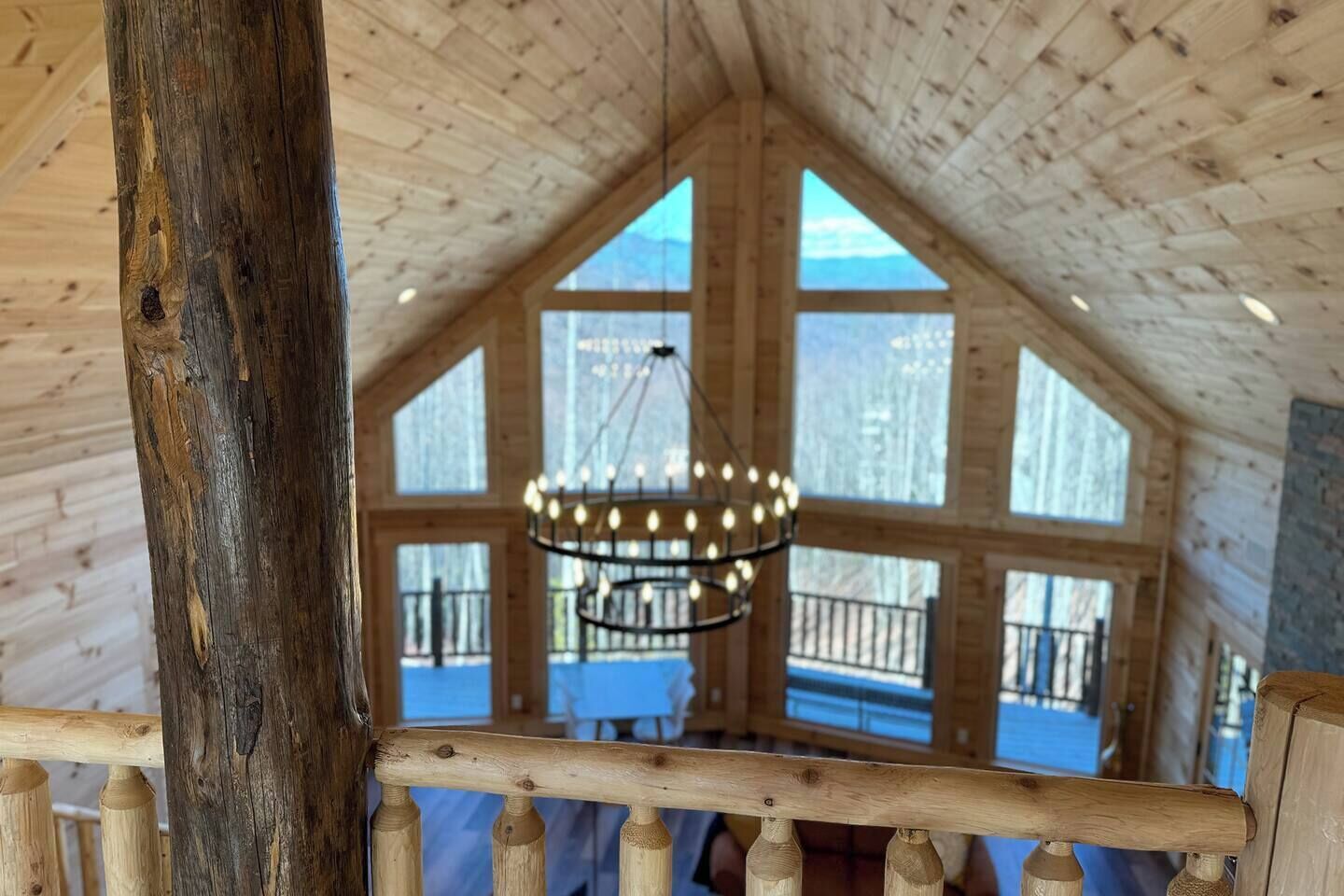 Ein Holzinnenraum mit großen Fenstern, einer Kandelaber und einer Holzgalerie.
