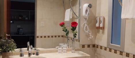 A bathroom with a sink, mirror, towel rack, hairdryer, and a potted plant.