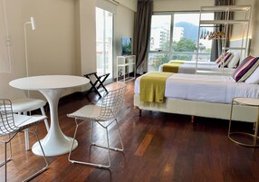 Una habitación de hotel moderna con una cama grande, una mesa redonda para comer y un área de estar con sillas.