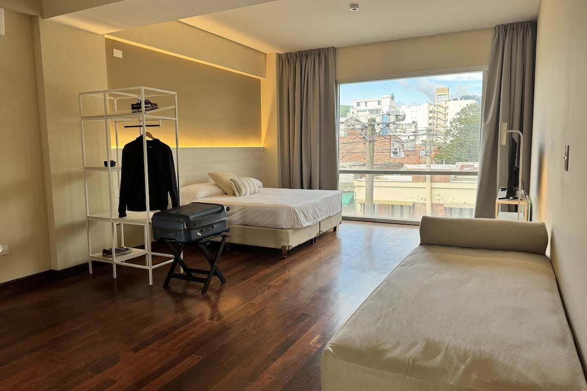 Una habitación de hotel con cama, zona de estar, armario y maleta.