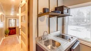 A modern kitchen with a stainless steel sink, a built-in stovetop, and overhead shelves. - Quiet Country Studio Between Saugatuck & Holland! (Holland)