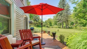 A wooden deck with a red umbrella, a wooden chair, and a table with candles. - Quiet Country Studio Between Saugatuck & Holland! (Holland)
