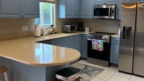 Une cuisine avec des meubles de couleur bleue, un réfrigérateur en acier inoxydable, un four à micro-ondes et une cuisinière.