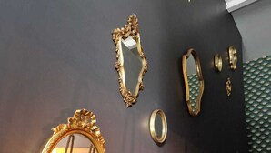 A staircase with a dark wall, a round mirror with an ornate frame, and a geometric patterned wall. - Gîte Bien-être Avec Jacuzzi & Sauna à la Campagne (Saint-Victurnien)