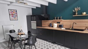 A modern kitchen with black cabinets, a wooden countertop, and a black stove. - Gîte Bien-être Avec Jacuzzi & Sauna à la Campagne (Saint-Victurnien)