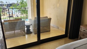 A hotel room with a balcony, wicker furniture, and a view of a pool and landscape. - Welcome to Your Dream Getaway at Grand Solmar Pacific Dunes, Cabo! (Cabo San Lucas)
