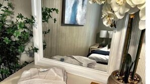 Un baño con tocador blanco, un espejo, una orquídea en maceta y una báscula digital.