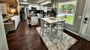 Una cocina moderna con comedor, suelo de madera y un amplio ventanal con vistas al exterior.