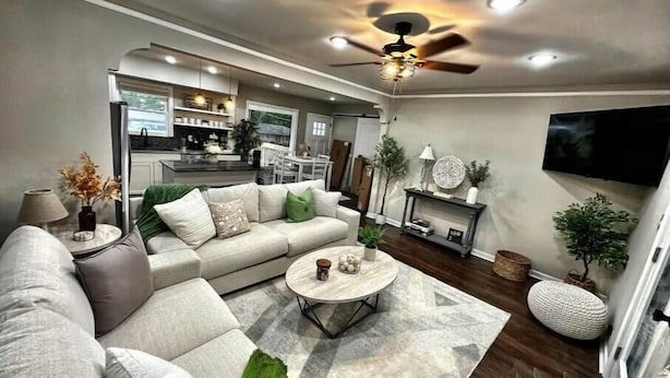 Una sala moderna con un sofá modular, una mesa de centro y un televisor montado en la pared.