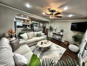 A modern living room with a sectional sofa, a coffee table, and a TV mounted on the wall.
