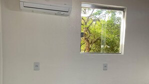 A bedroom with a bed, an air conditioner, a window, and a power outlet. - Hotel Suelen (Itacoatiara)