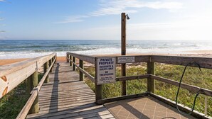 A wooden boardwalk leading to a beach with a sign indicating it is private property for residents and guests only.