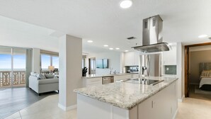 A modern kitchen with a large island, built-in appliances, and a view to the living area.