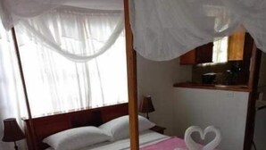 A four-poster bed with a canopy, a pink towel, and two white swan-shaped towels on the bed. - Castara Bliss Apartments B (Tobago)