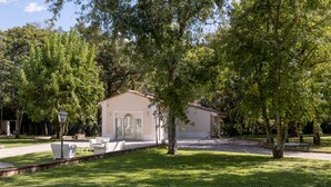 Un petit bâtiment d’un seul étage, à la façade de couleur beige, entouré d’une pelouse bien entretenue et d’arbres.