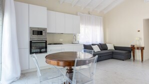 Une cuisine moderne avec des meubles blancs, une table à manger en bois et des chaises transparentes.