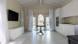 Une cuisine moderne avec des armoires blanches, un four encastré et une grande fenêtre ornée de vitraux.