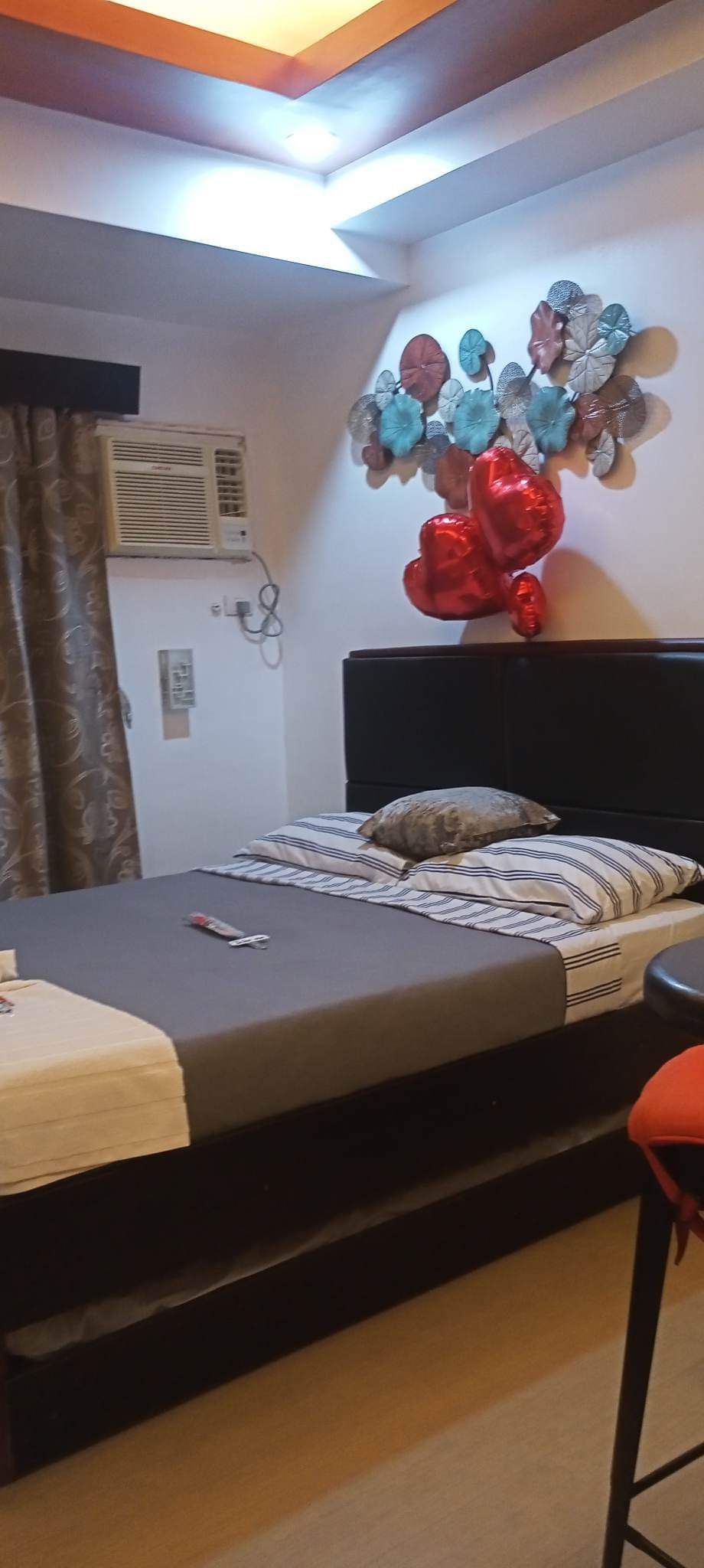 Quarto com cama, mesa de cabeceira, ar-condicionado fixado na parede e um objeto decorativo na parede.