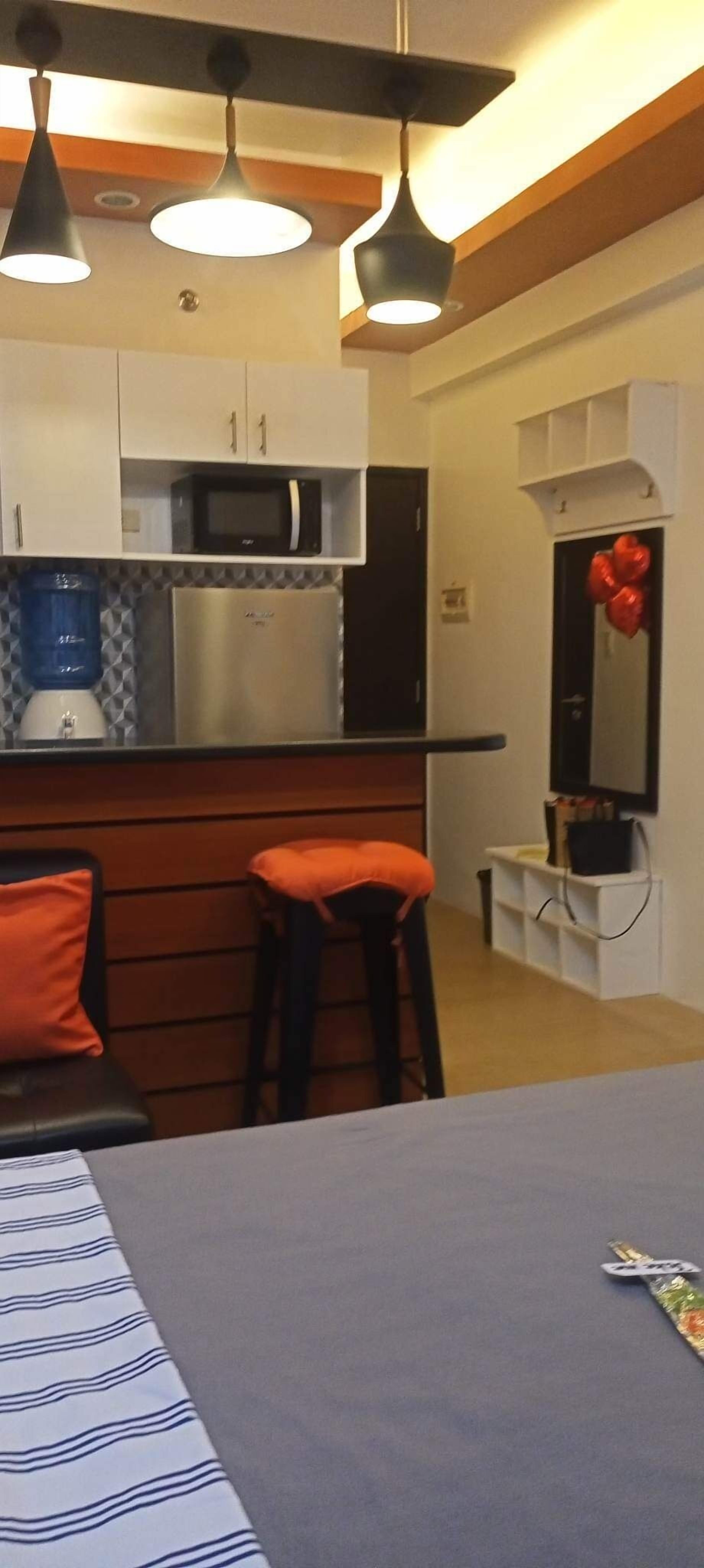 Una cocina compacta con microondas, refrigerador y taburetes de bar.