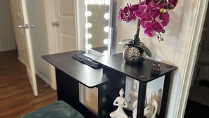 A vanity table with a mirror, a vase with flowers, and a remote control. - THE UPTOWN BUNGALOW-COVERED PARKING-Walkable Historic Neighborhood-PET FRIENDLY! (Dallas)