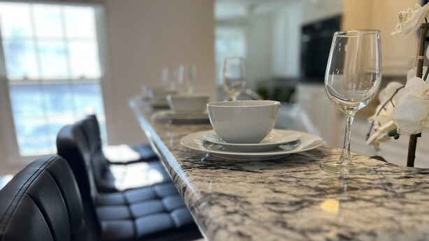 A dining area with a marble countertop, black leather chairs, and white tableware. - THE UPTOWN BUNGALOW-COVERED PARKING-Walkable Historic Neighborhood-PET FRIENDLY! (Dallas)