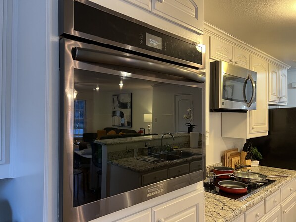 A modern kitchen with stainless steel appliances, a granite countertop, and white cabinetry.