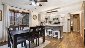 A spacious kitchen with wooden flooring, a dining area with dark wooden chairs, and a ceiling fan. - Charming Cottage on a hill by Camelback and Kalahari (Long Pond)
