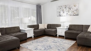 A modern living room with a sectional sofa, a patterned rug, and a painting on the wall. - Beautiful Home in Central Nampa (Nampa)