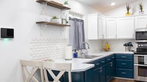 A modern kitchen with white cabinets, blue accents, and a built-in oven. - Beautiful Home in Central Nampa (Nampa)