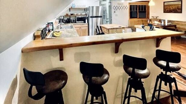 Una cocina con isla central, taburetes de bar y electrodomésticos modernos.