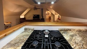 Una cocina con estufa a gas, encimeras de granito y una moderna campana extractora de acero inoxidable.