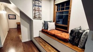 Un interior moderno con un banco empotrado a lo largo de una pared, un cartel y una escalera que lleva a otra habitación.