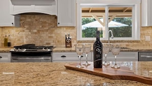A kitchen with granite countertops, a wine bottle, and glasses on a wooden board. - Private Villa W/ Pool/spa, GameBarn, 4300 sq ft- Perfect for families and large groups (Twain Harte)