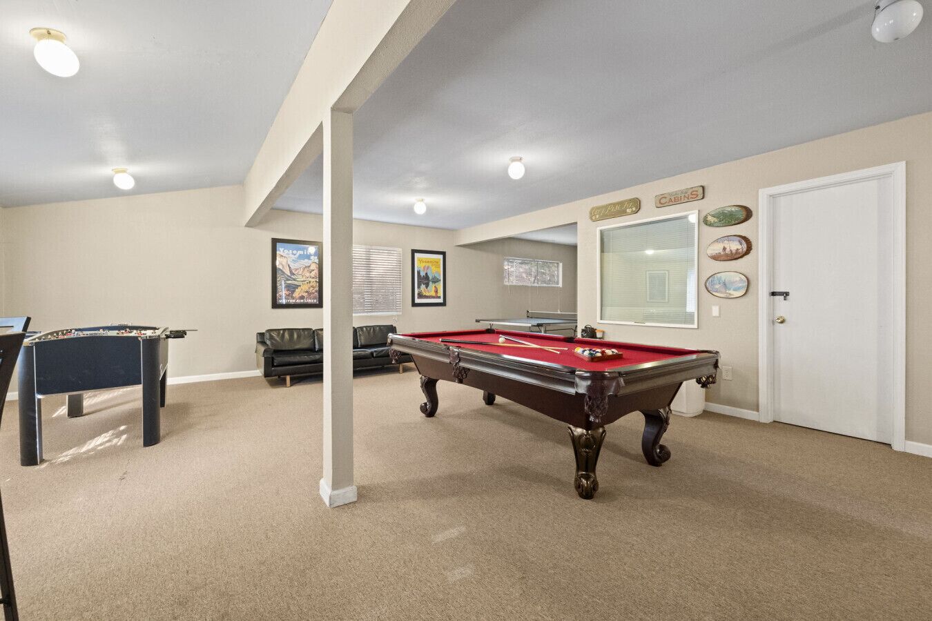 A pool table in a room with a sofa and a foosball table.