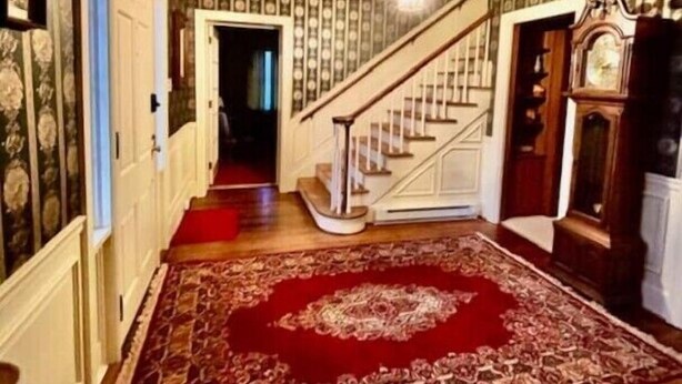 A spacious foyer with a grand staircase, a red patterned carpet, and a chandelier. - Victorian Oasis home in Mineral City, near Atwood - Deer Hunting -  Hot Tub (Mineral City)