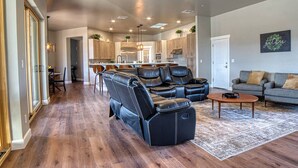A spacious living room with a black leather sectional sofa, a grey sofa, and a coffee table. - Event Ready Spacious Tucson Villa w/ Private Pool (Tucson)
