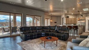 A spacious living room with a sectional sofa, a coffee table, and a view of the backyard through large sliding glass doors. - Event Ready Spacious Tucson Villa w/ Private Pool (Tucson)