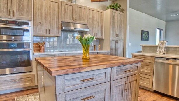 A modern kitchen with wooden cabinets, stainless steel appliances, and a central island with a vase of flowers. - Event Ready Spacious Tucson Villa w/ Private Pool (Tucson)