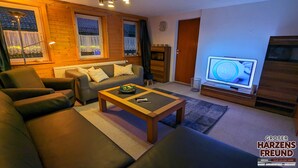 A cozy living room with a sofa, a coffee table, and a television.