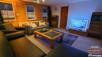Ein gemütliches Wohnzimmer mit einer Couch, einem Couchtisch und einem Fernseher.